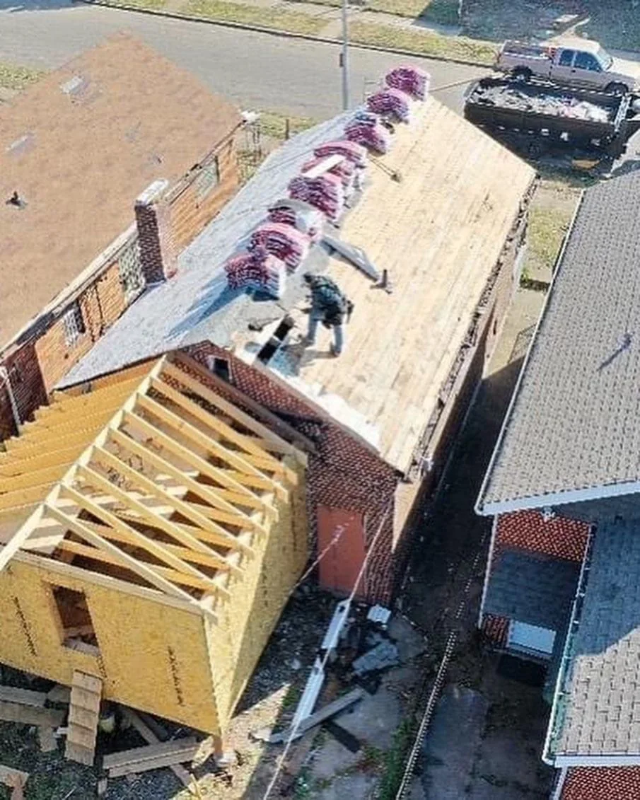 Timber frame and roof trusses of a new home addition being built onto an existing brick house