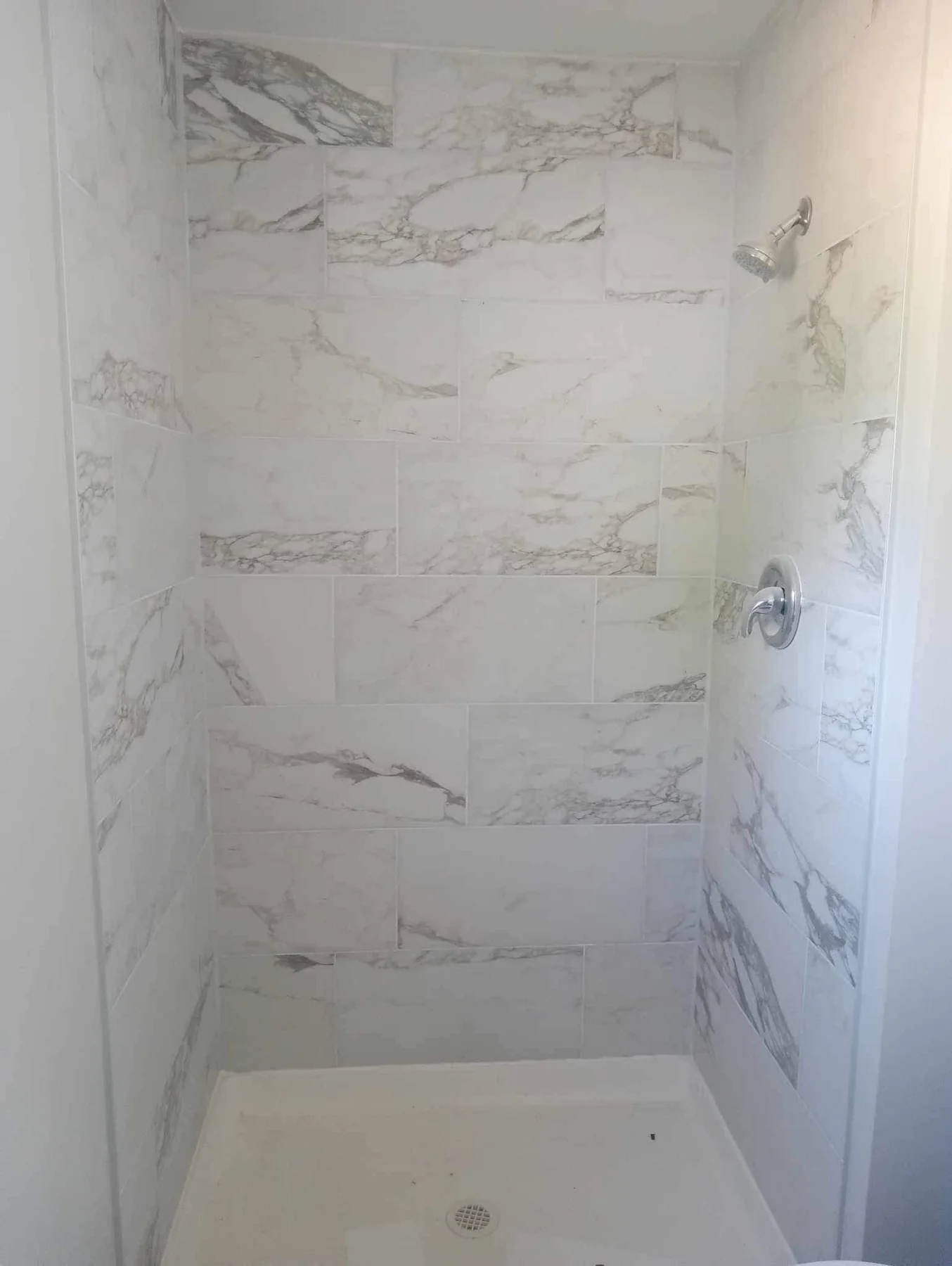 New walk-in shower finished in marble-look wall tiles with a tiled shower floor
