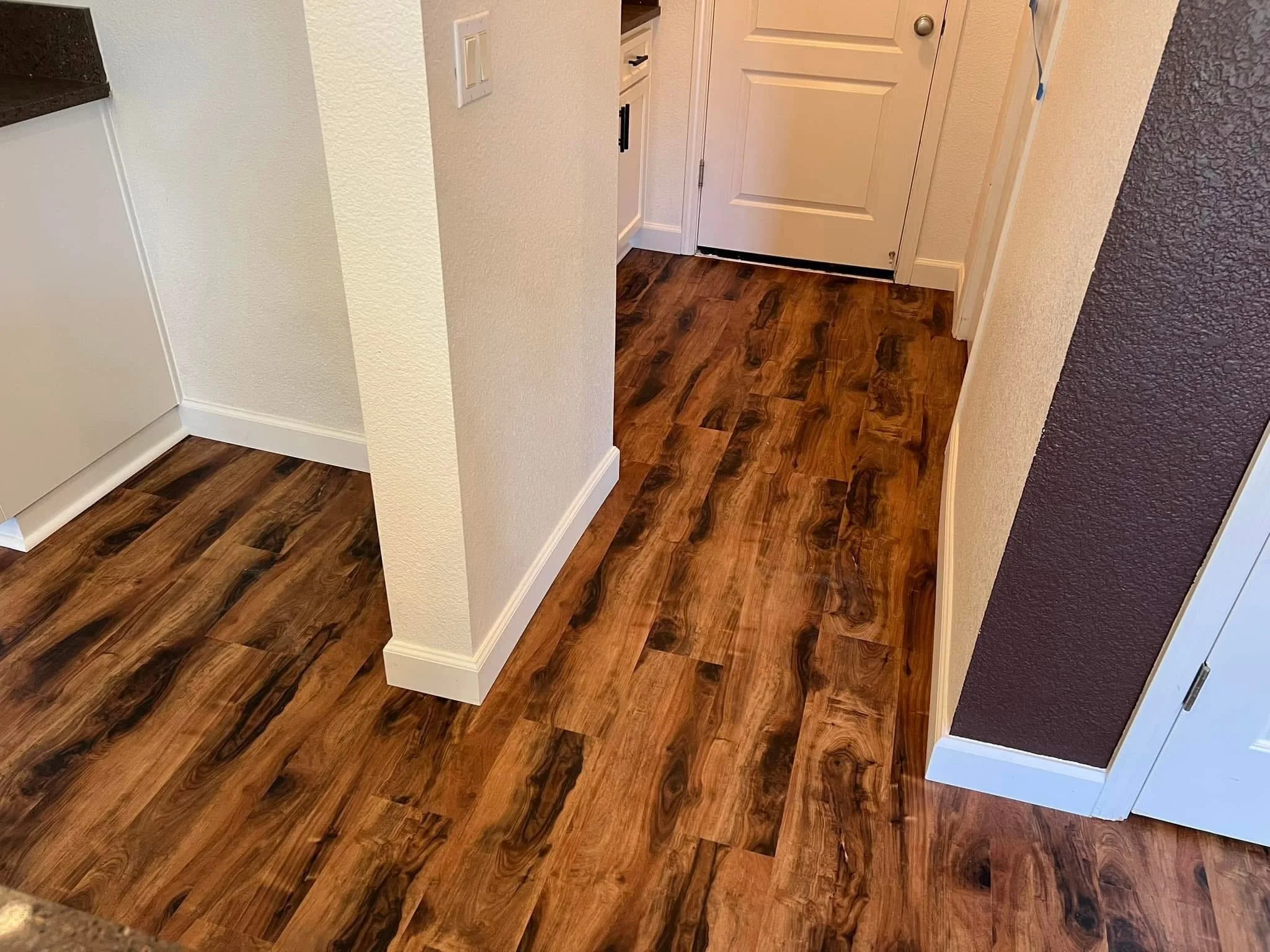 New wood-look plank flooring through a home entryway and hallway